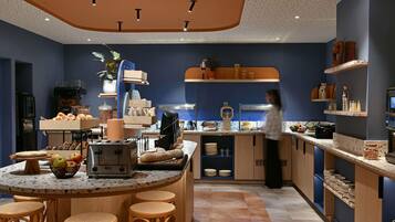 Una cocina moderna con una isla central, taburetes de bar y una persona preparando comida.