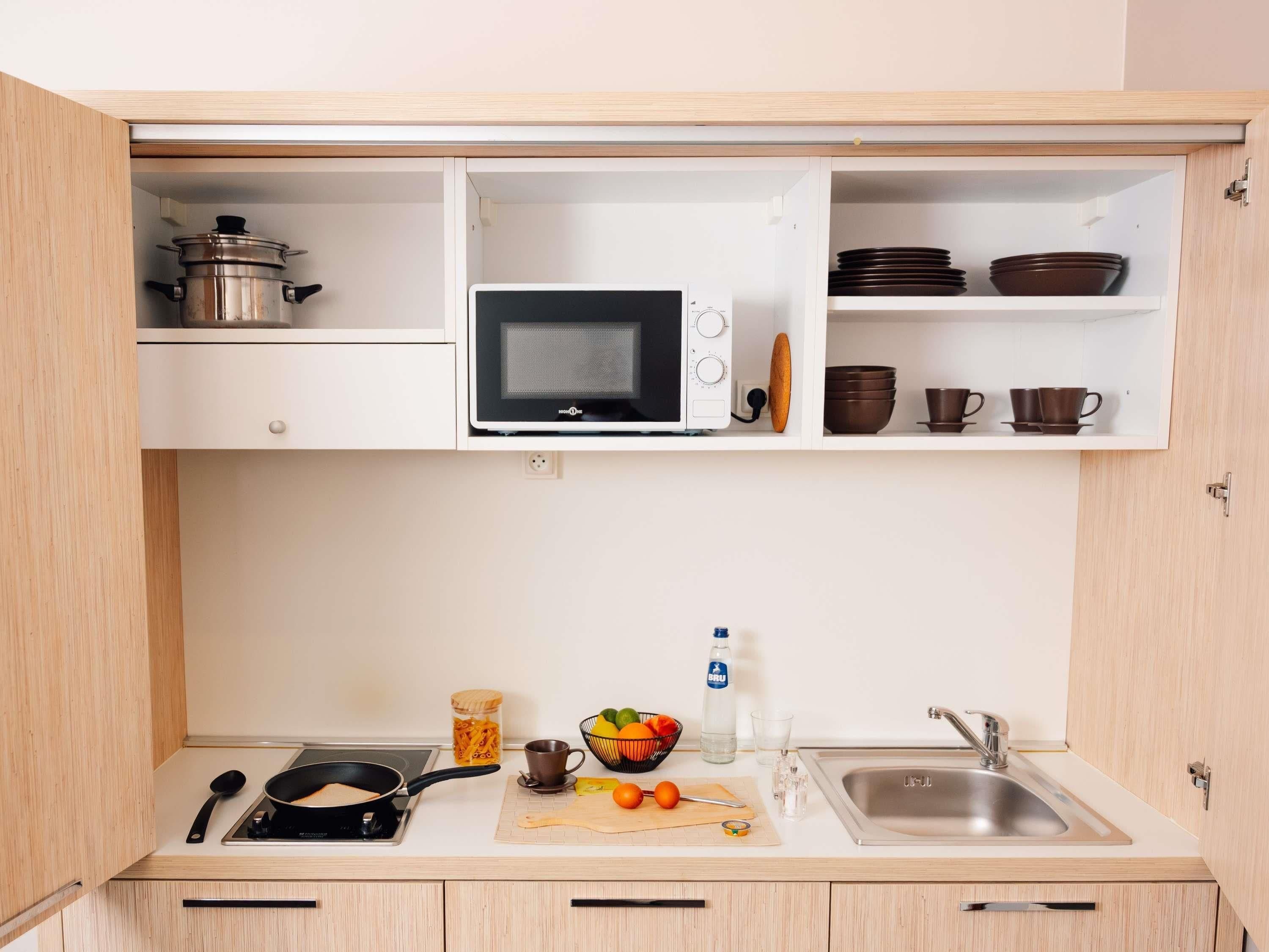 A compact kitchen with a microwave, stove, and sink.