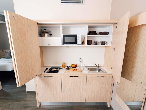 A compact kitchenette with a microwave, stove, and sink. - Ibis Styles Charleroi Airport Aero44 (Charleroi)