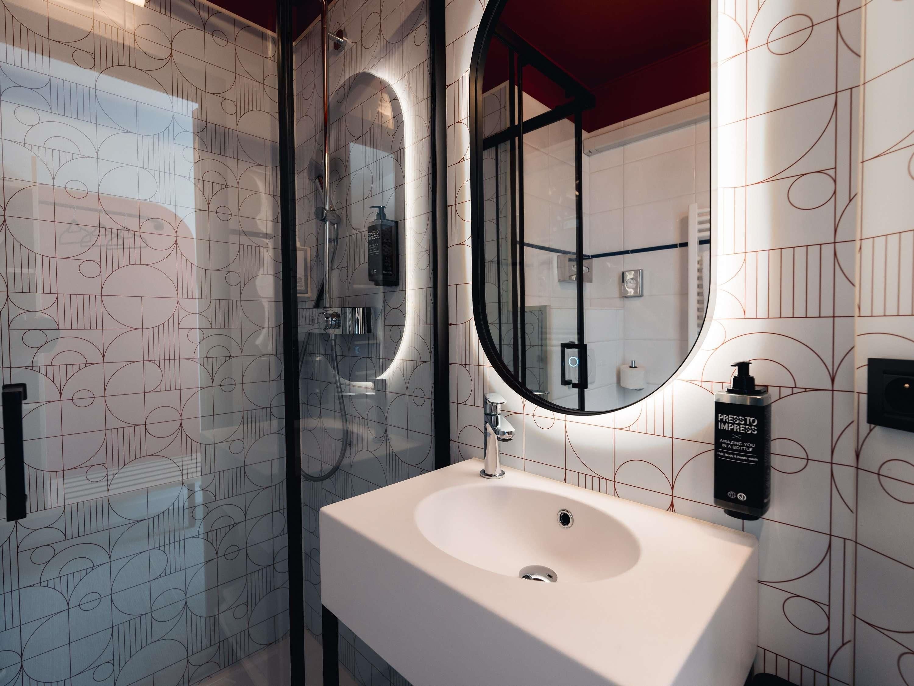 A modern bathroom with a glass shower enclosure, a white sink, and a large mirror.