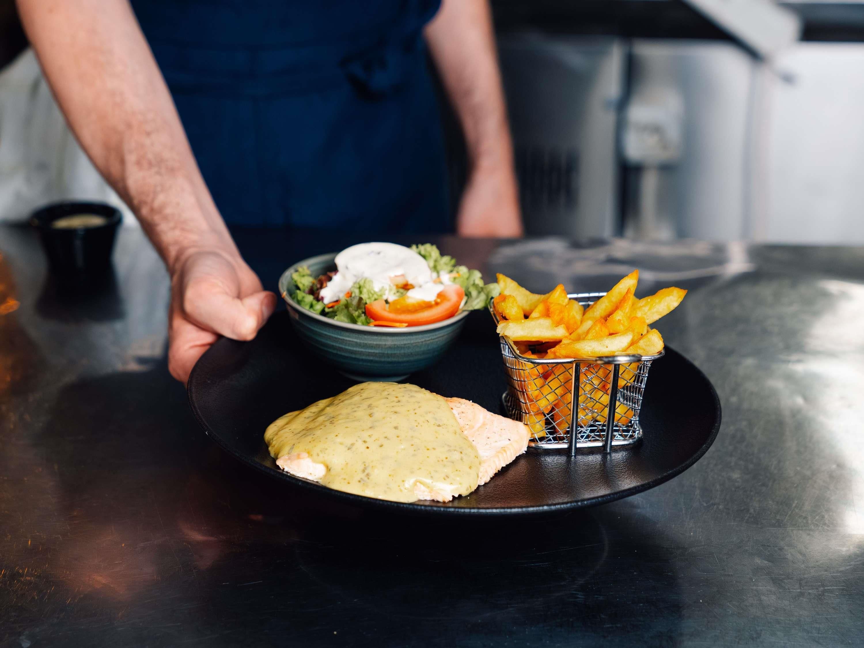 A plate with a sandwich, a bowl of salad, and a basket of fries.