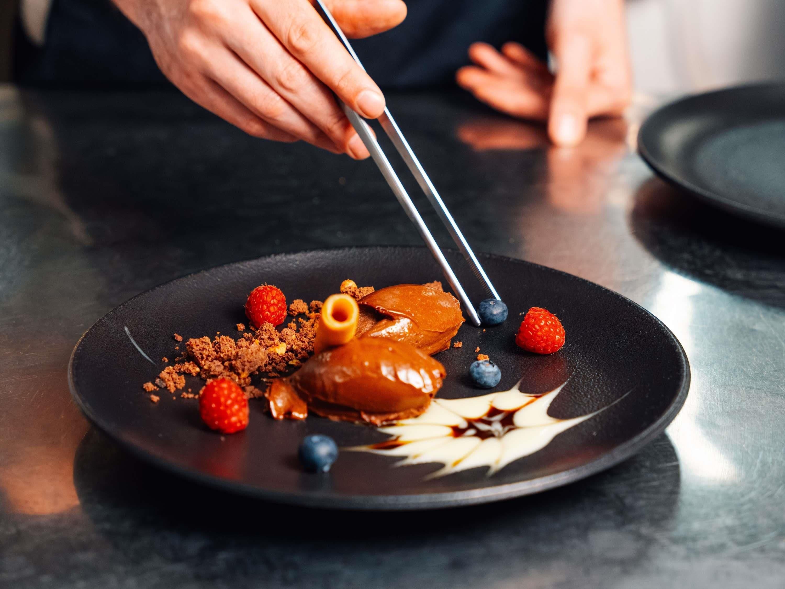 En desserttallerken med karamelliseret wienerbrød, hindbær og chokoladedrys.