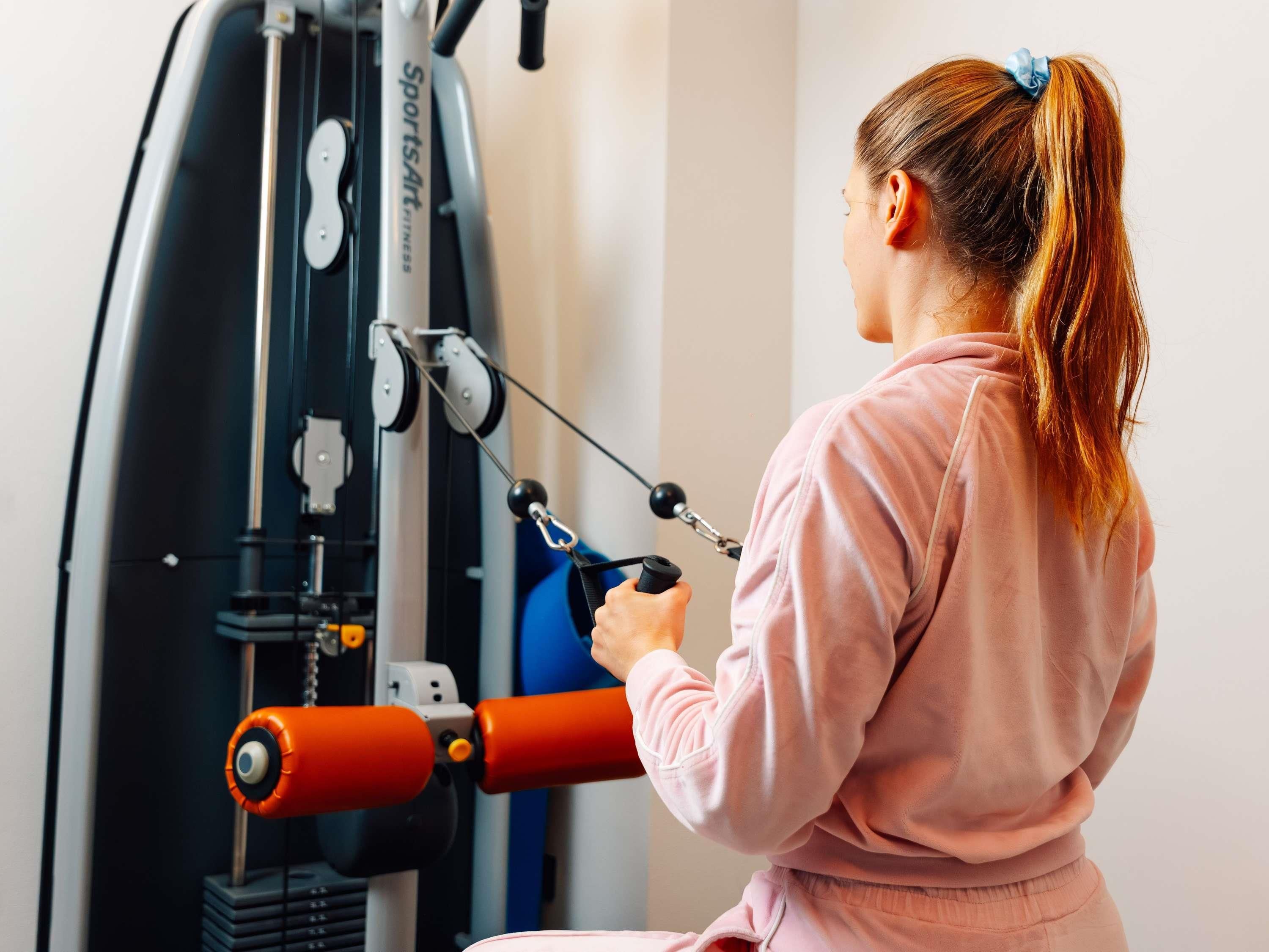 Una persona usando una máquina de gimnasio con sistema de poleas.
