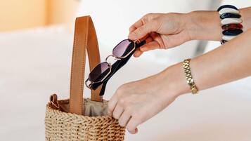 Una mano guardando gafas de sol en una bolsa tejida.
