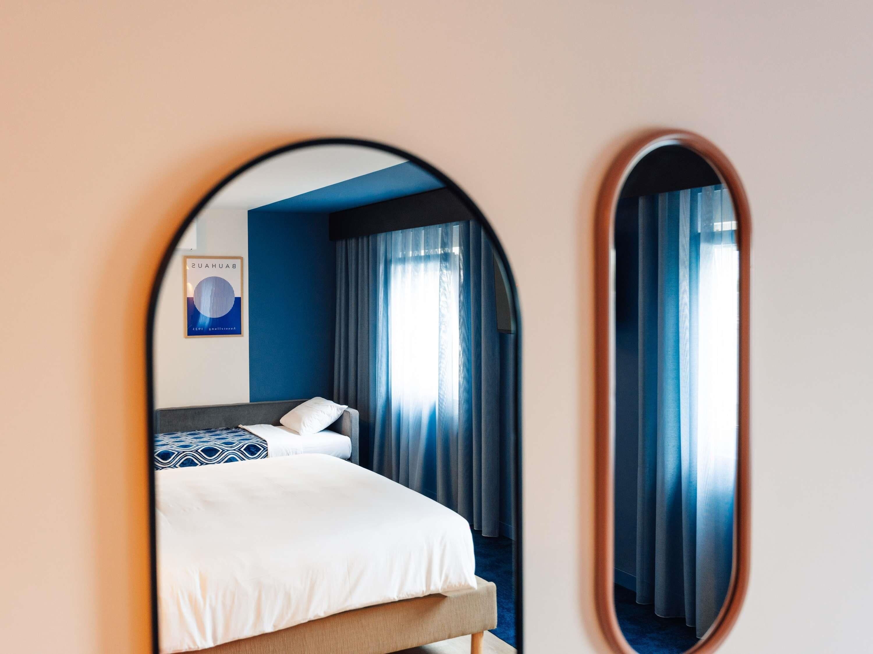 A hotel room with a bed, a pillow, a wall-mounted picture, and a window with curtains.
