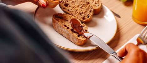 Una persona untando mantequilla de cacahuete en una rebanada de pan sobre un plato.