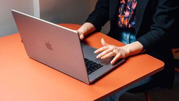 A person using a laptop on an orange table.