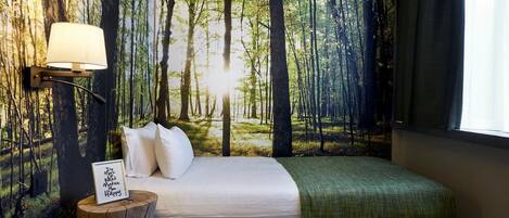 Un dormitorio con un mural temático de bosque, una cama con sábanas blancas, un plaid verde y una lámpara de noche.
