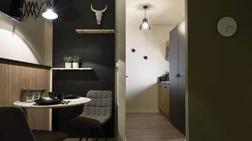 Une cuisine compacte avec une table de salle à manger ronde, deux chaises, un luminaire suspendu et une horloge fixée au mur.