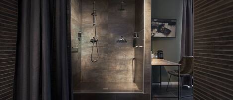A modern bathroom with a walk-in shower, a small seating area, and a visible sink.