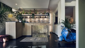 Un área de recepción moderna con una pared de diseño en patrón chevron, un mostrador de recepción y una patineta azul estacionada a un lado.