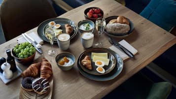 Ein Frühstückstisch mit Croissants, Eiern, Joghurt und einer Schale Trauben.