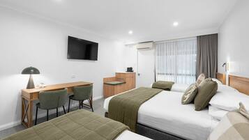 A hotel room with two beds, a desk, a chair, a TV, and a window with curtains.