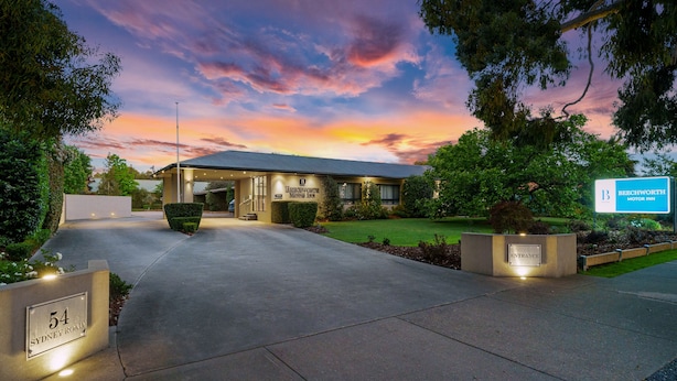 A modern hotel entrance with a well-maintained driveway, a sign indicating the hotel name, and a clear view of the surrounding greenery. - Beechworth Motor Inn (Beechworth)