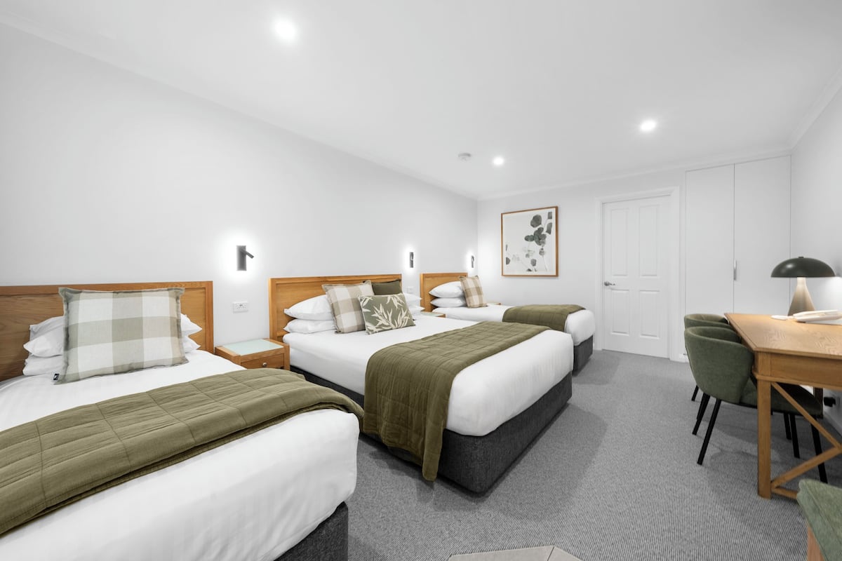 A hotel room with two beds, a desk, and a chair.