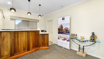 A reception area with a wooden reception desk, pendant lighting, a glass display case, and a promotional poster for Beechworth.