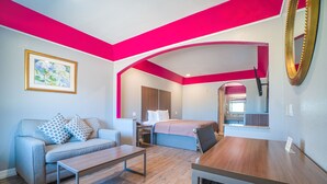 A modern room with a sofa, a bed, a wooden table, and a mirror. - Hotel Bliss Kemah (Kemah)