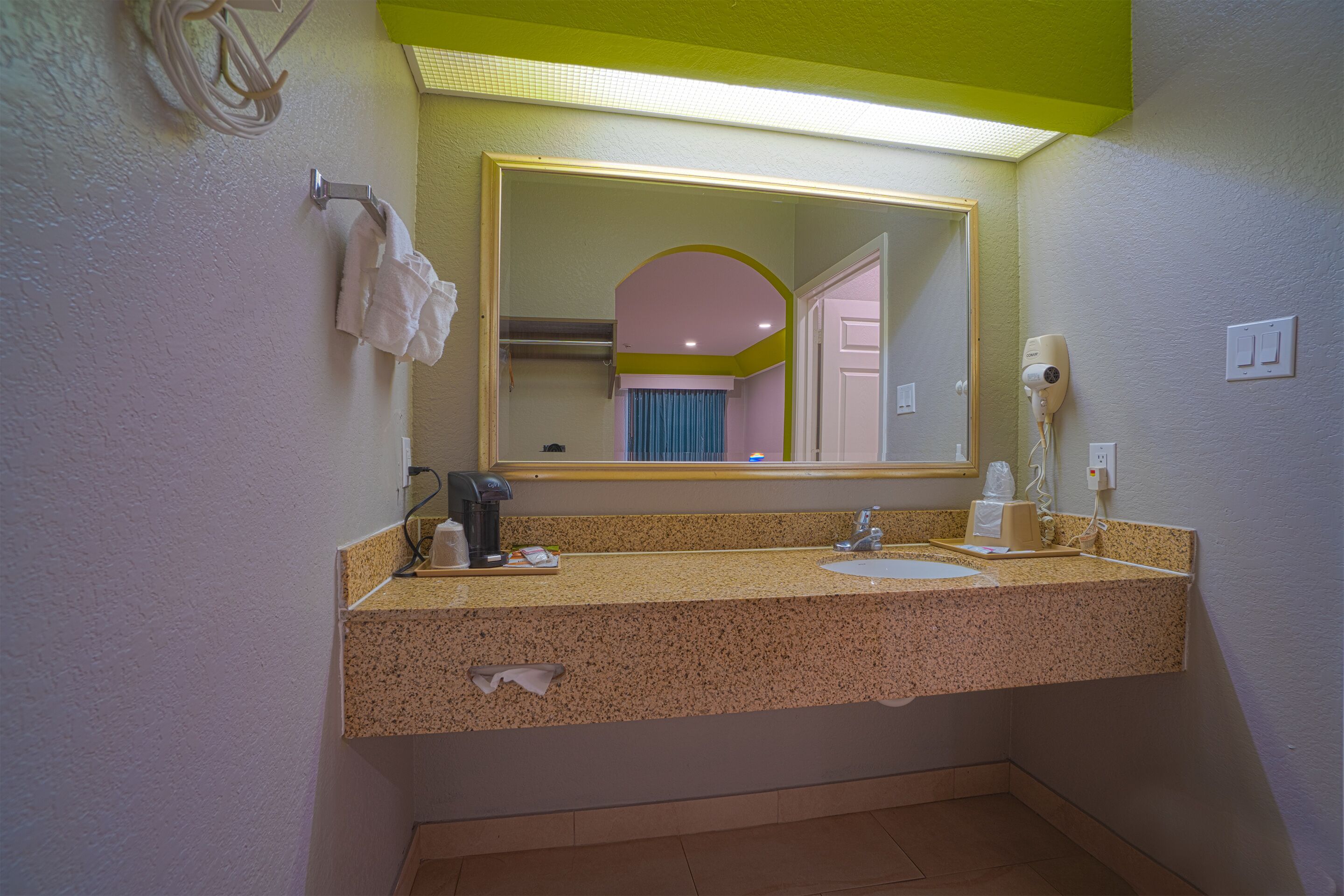 A bathroom with a sink, mirror, towel rack, and hairdryer.