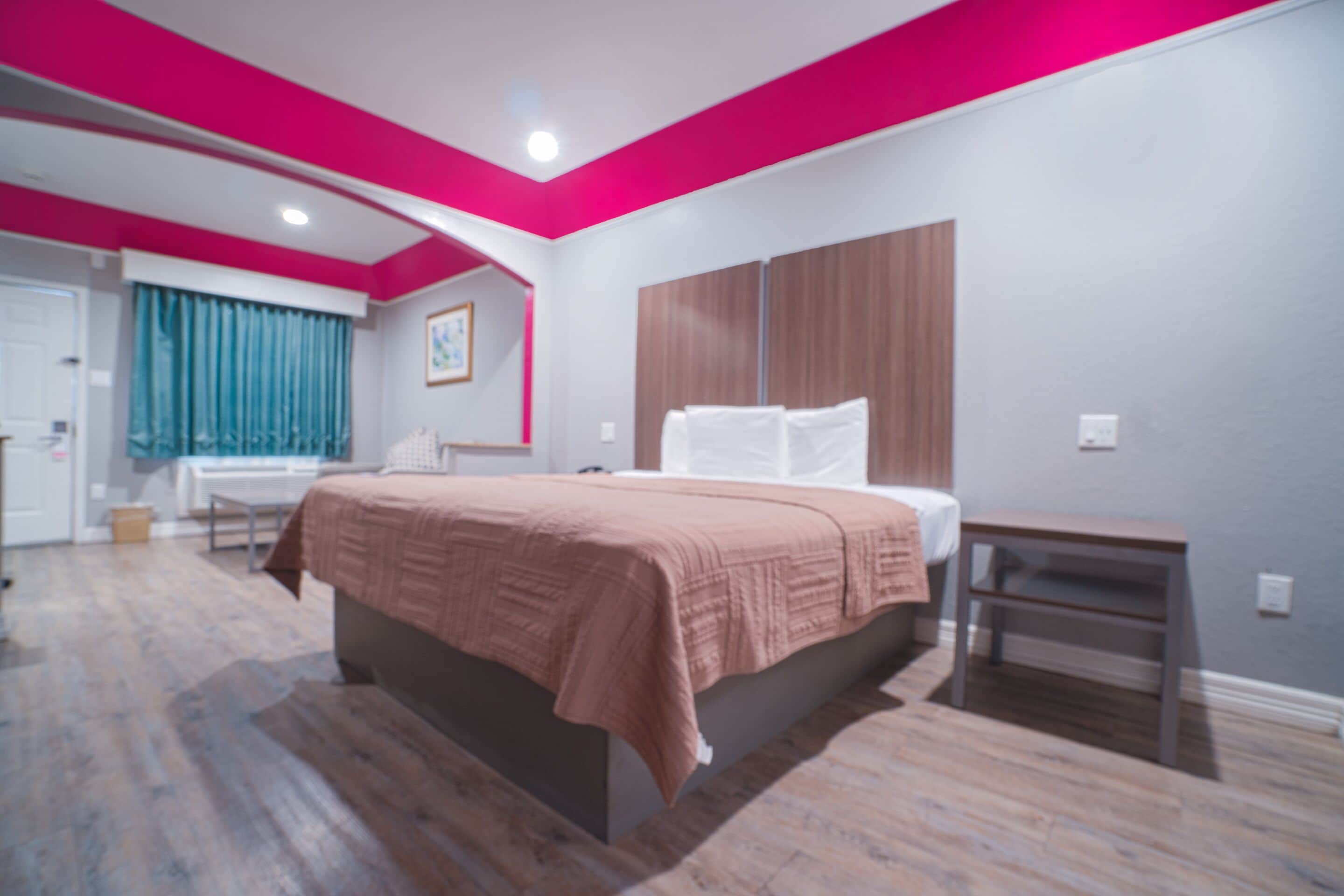 Un dormitorio con cama, mesita de noche, armario y ventana con cortinas.