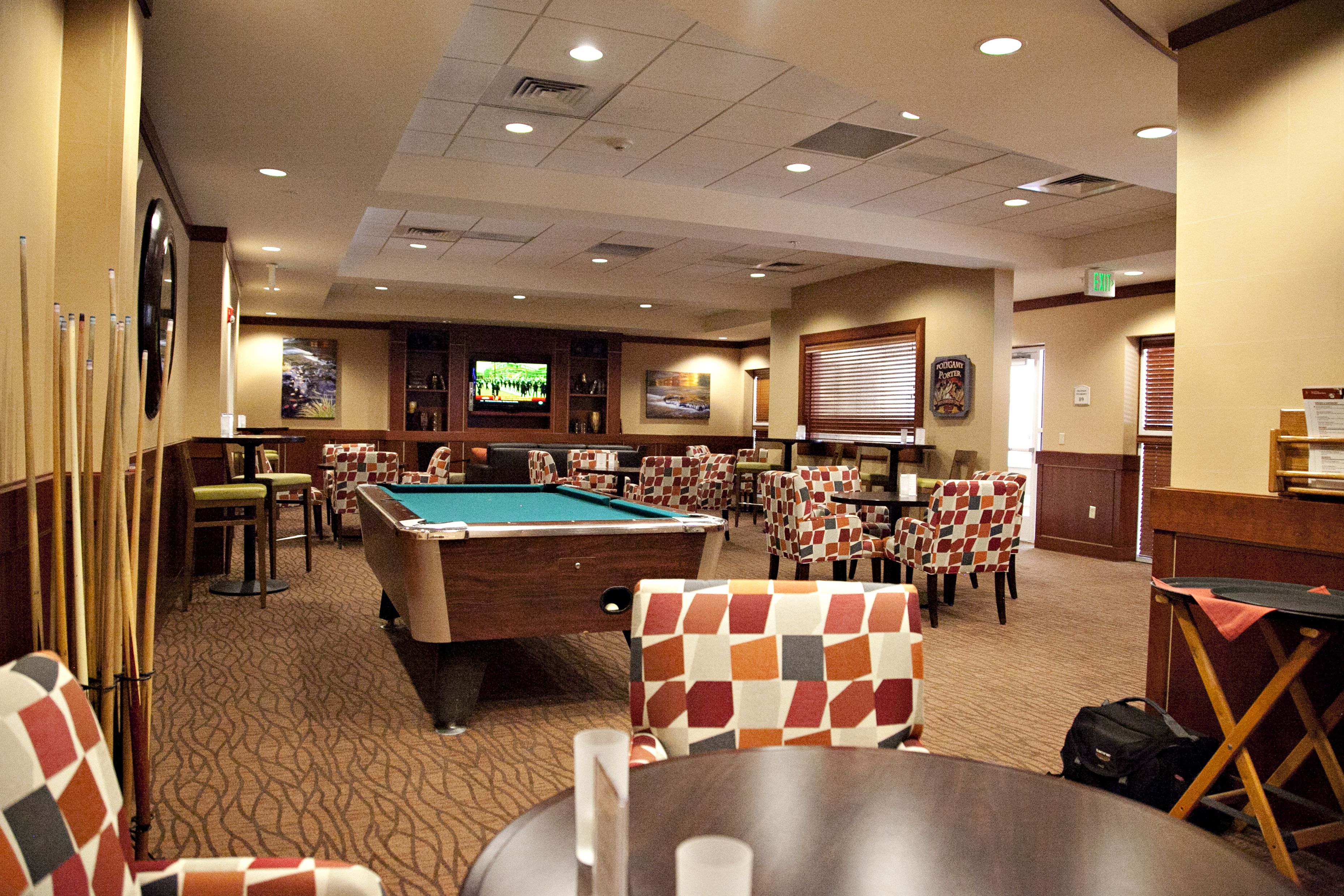 A pool table in a room with multiple chairs and a television screen.