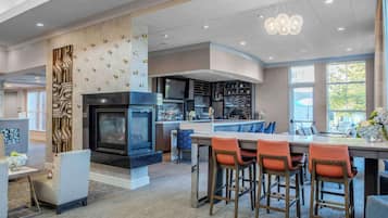 A modern kitchen with a central island, bar area with stools, and a fireplace.