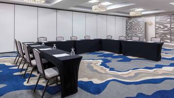 A conference room with a long table, chairs, and a patterned carpet.