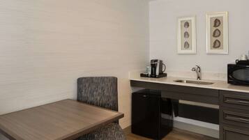A compact kitchenette with a small table, a built-in sink, a microwave, and a coffee maker.