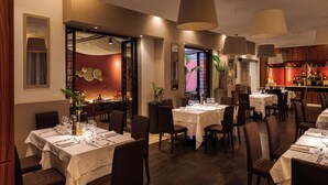 Ein Restaurant mit mehreren Essplätzen, das ein warmes Farbkonzept und moderne Einrichtungsdetails bietet.