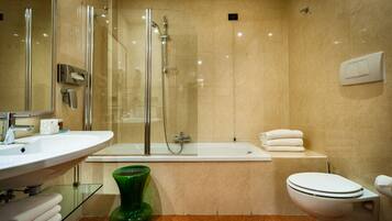A modern bathroom with a glass-enclosed shower, a white bathtub, and a toilet.