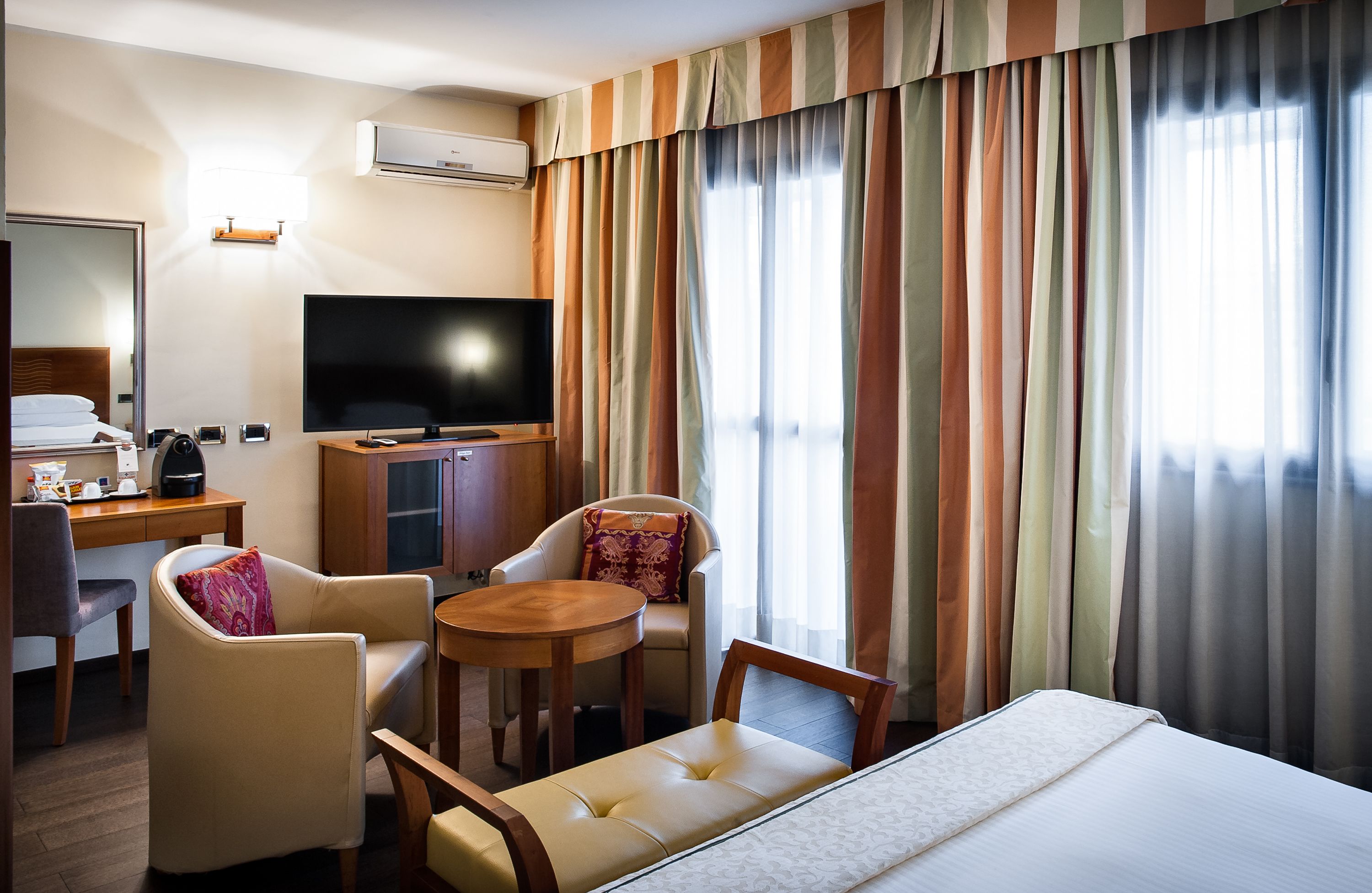 Una camera d'albergo con un letto, una televisione, una scrivania e una sedia.