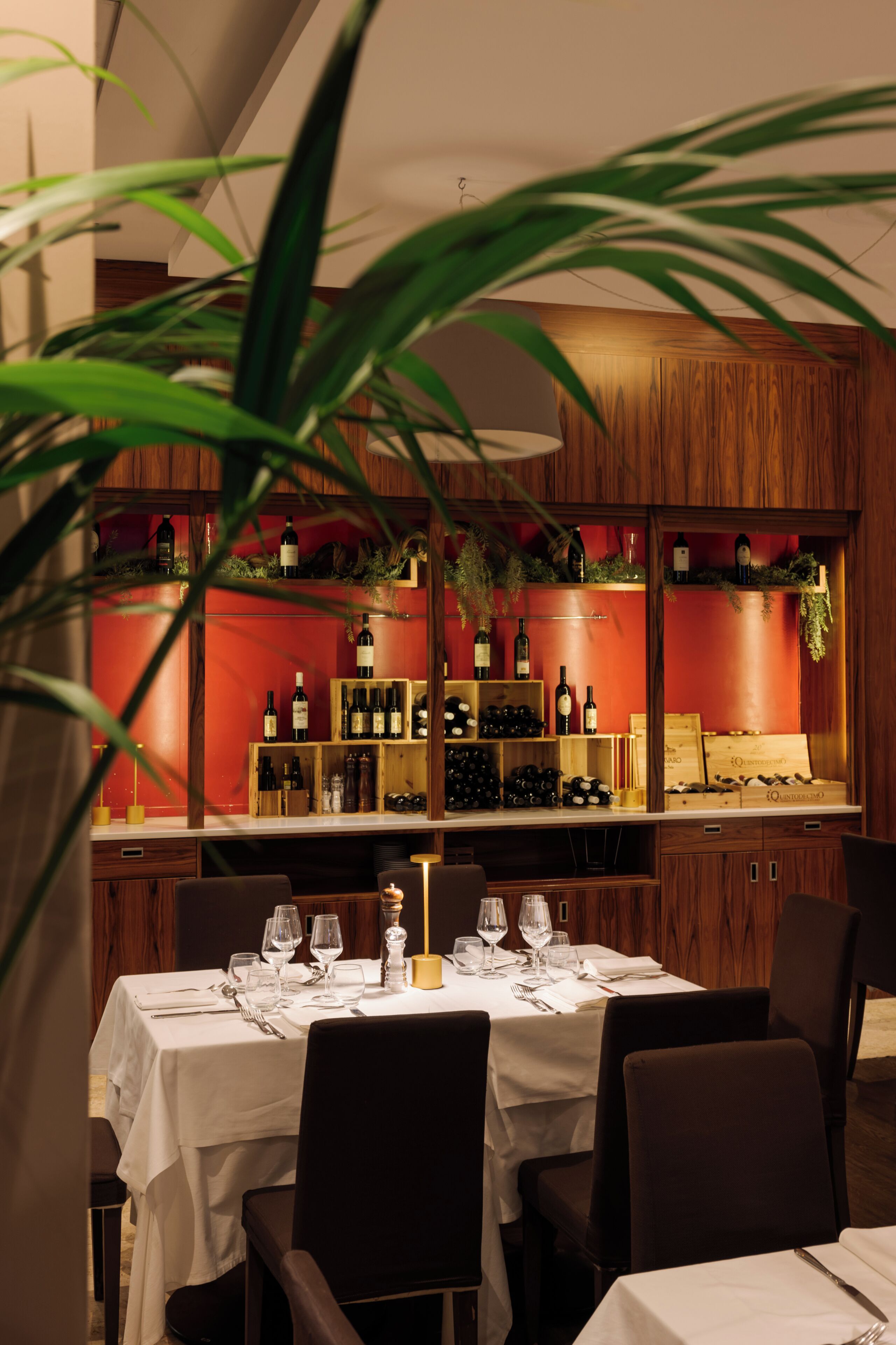 A restaurant with a wooden interior, white tablecloths, and a wine display.