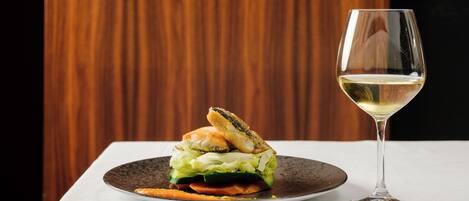 Un plato con un sándwich y una copa de vino blanco sobre una mesa.