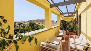 Ein Balkon mit gelben Wänden, weißen Möbeln und Topfpflanzen.