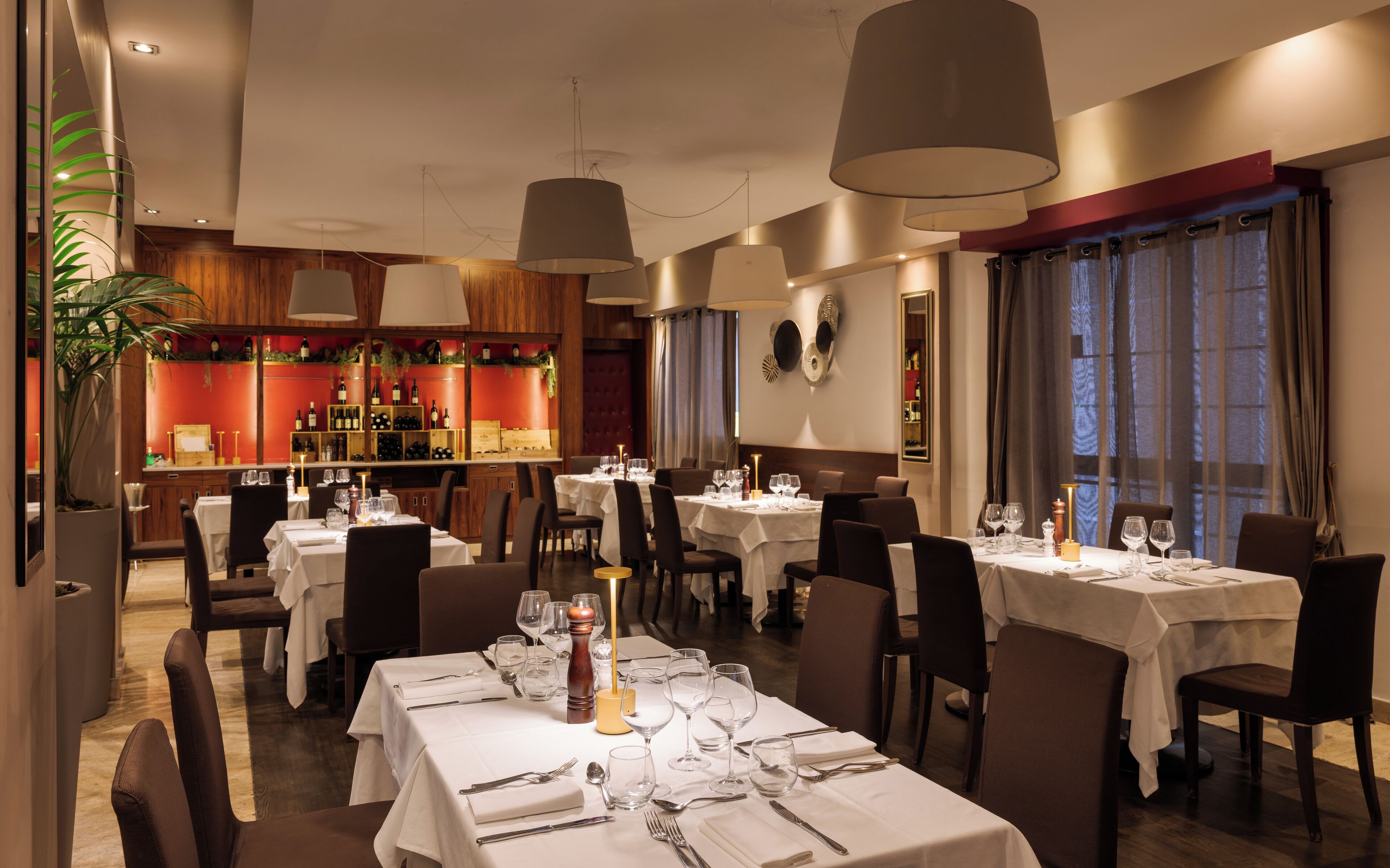 Un restaurant doté de nombreuses tables dressées pour le service, offrant une ambiance chaleureuse et un décor en bois.