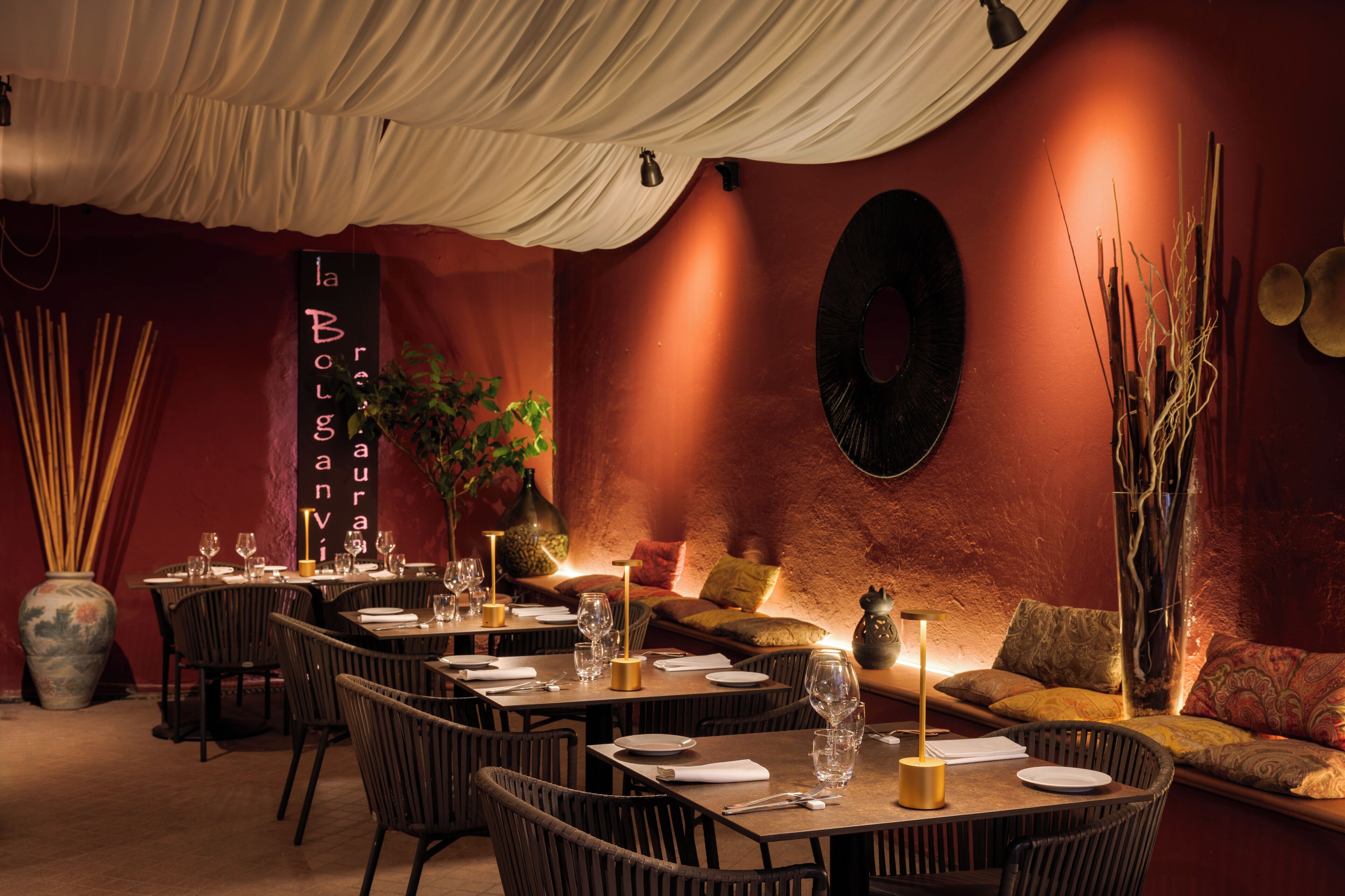 Un restaurante con mesas dispuestas para comer, un área con sofás y detalles decorativos como un florero y cuadros en la pared.