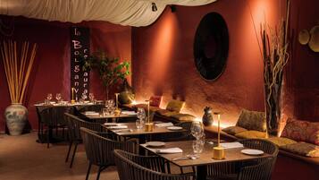 Un restaurante con mesas dispuestas para comer, un área con sofás y detalles decorativos como un florero y cuadros en la pared.