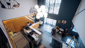 A modern hotel lobby with a high ceiling, a reception desk, a seating area, and a staircase. - Hotel Euro Suite Curitiba Batel By Nacional Inn (Curitiba)
