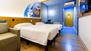 A hotel room with two beds, a sofa, a large wall mural, an air conditioning unit, and a hallway leading to another room. - Hotel Euro Suite Curitiba Batel By Nacional Inn (Curitiba)