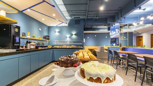 A modern cafe with a counter, seating area, and a display of cakes. - Hotel Euro Suite Curitiba Batel By Nacional Inn (Curitiba)