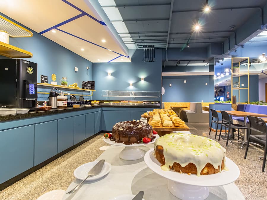 Un café moderno con mostrador, zona de asientos y una exhibición de pasteles.