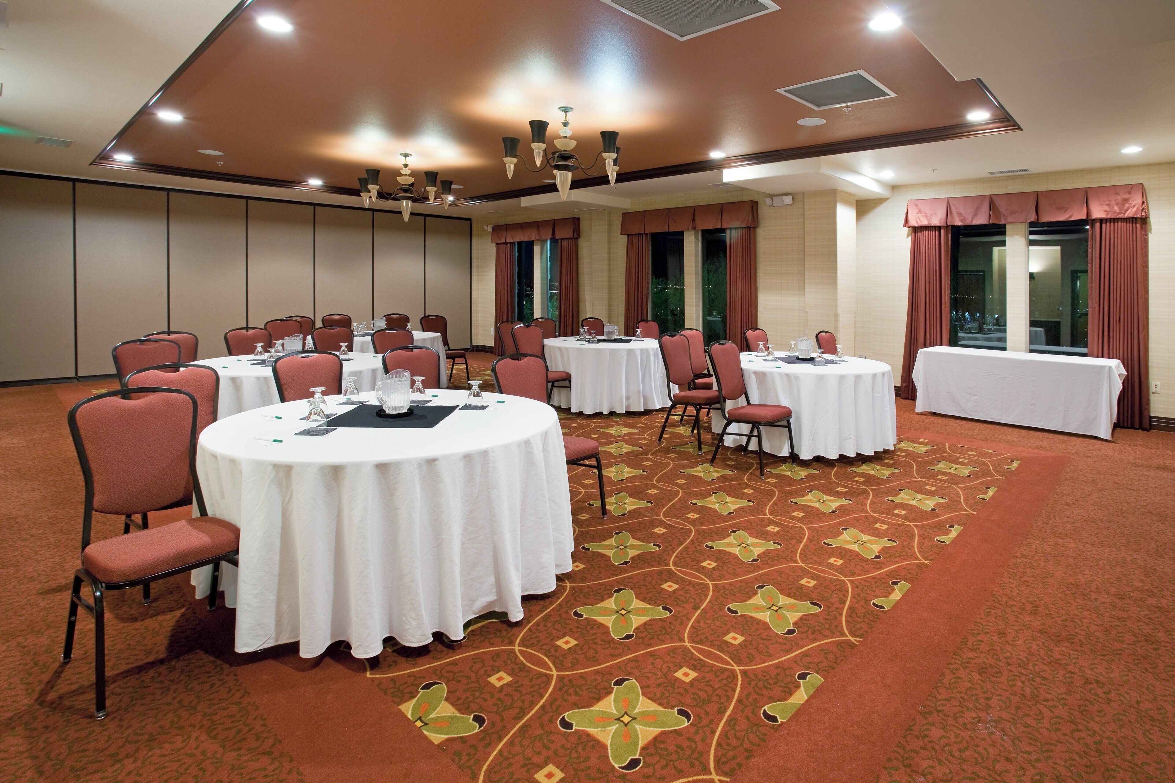 Une salle de conférence avec des tables rondes, des chaises et un tapis à motifs.
