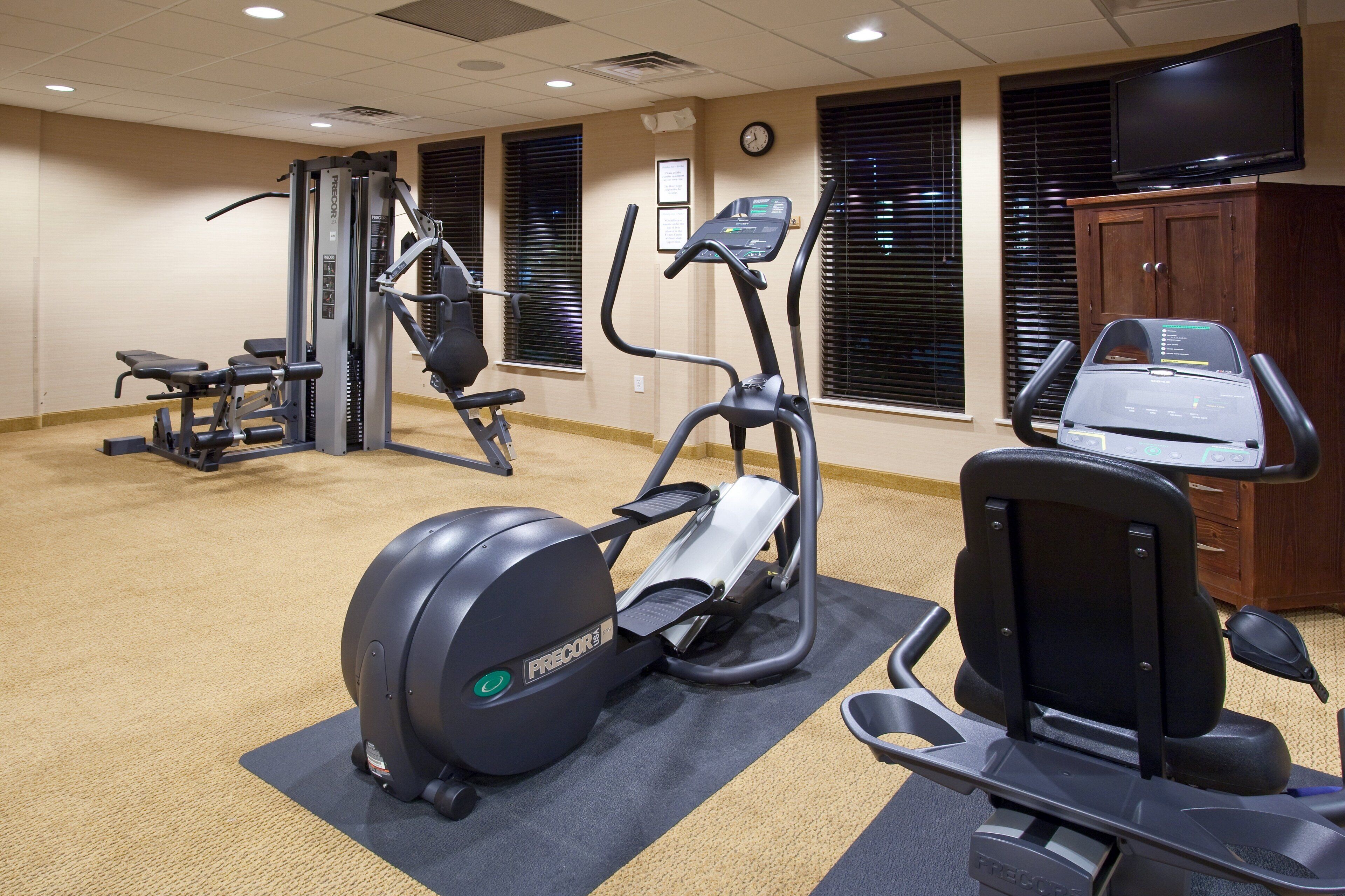 A gym with various exercise equipment including a stationary bike, elliptical, and weight machines.
