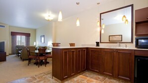 A modern kitchen with wooden cabinets, a large mirror, and pendant lighting.