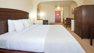 Een hotelkamer met een groot bed, een houten garderobe, een bureau en een stoel.