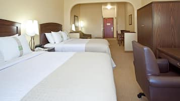A hotel room with two beds, a desk, a chair, and a wardrobe.