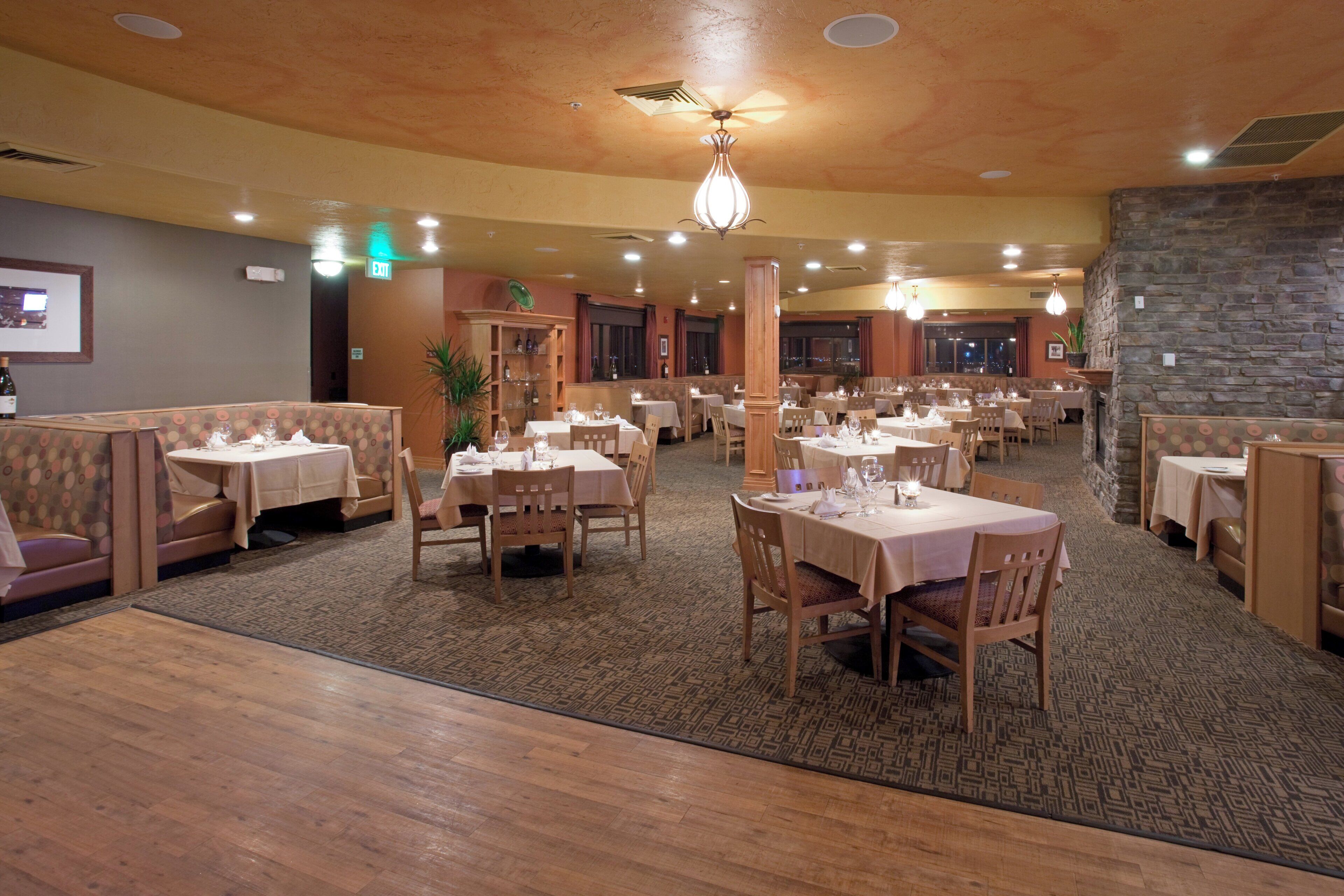 Un restaurante con varias mesas y cabinas, piso alfombrado y pared de piedra.