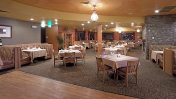 Un restaurante con varias mesas y cabinas, piso alfombrado y pared de piedra.