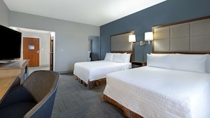 Une chambre d’hôtel avec deux lits, un bureau et une télévision.