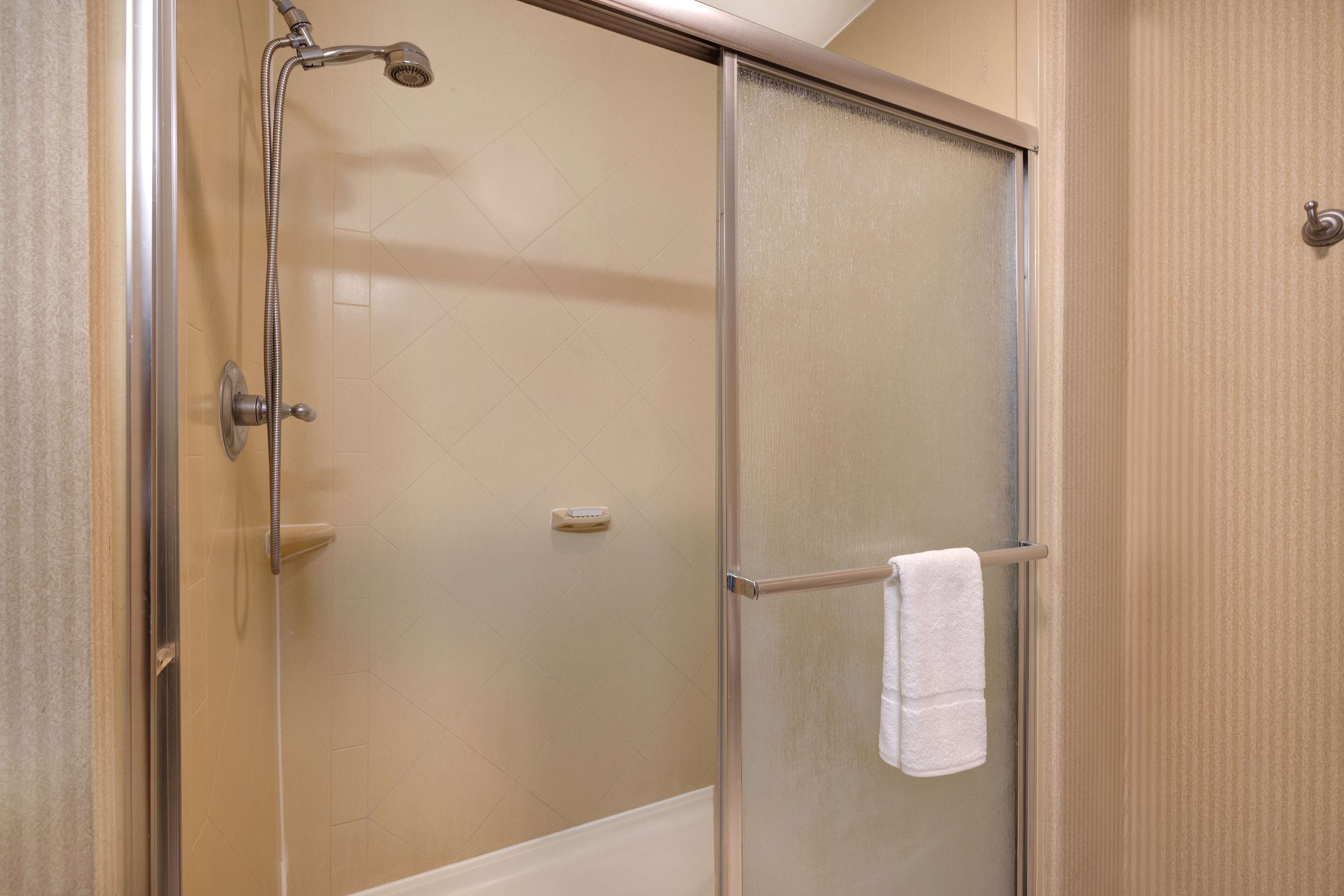 A glass-enclosed shower with a towel rack and a control panel.