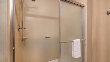A glass-enclosed shower with a towel rack and a control panel.